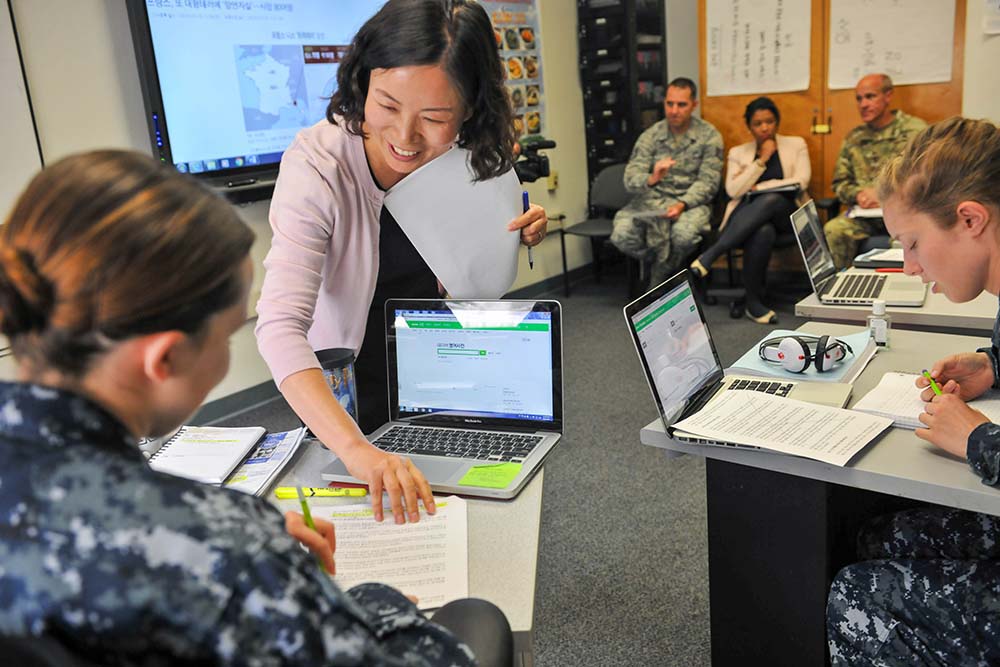 The Korean instructor eagerly helps her student while visitors look on during the visit to the Korean school Monday. (photo by Natela Cutter)